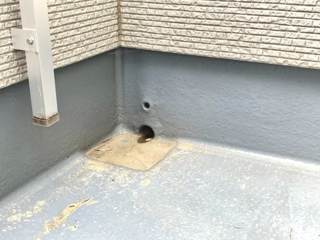 ベランダ排水口にたまった落ち葉と泥汚れ
